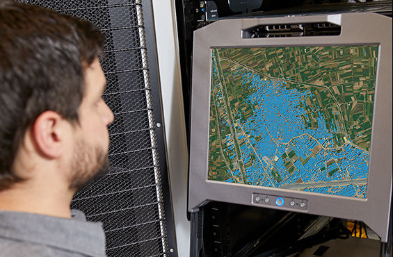 Photo of a man looking at a computer screen displaying map data.
