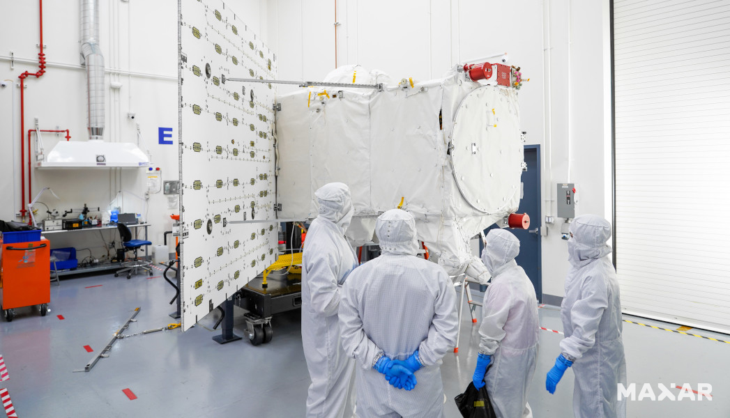 People observing spacecraft in a satellite manufacturing facility clean room